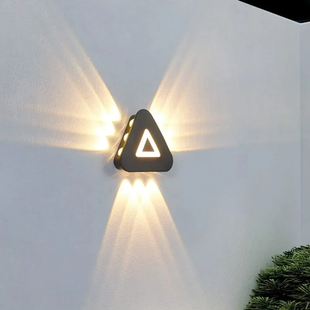 Triangular LED wall sconce lit in warm white, casting an angled wash on the wall
