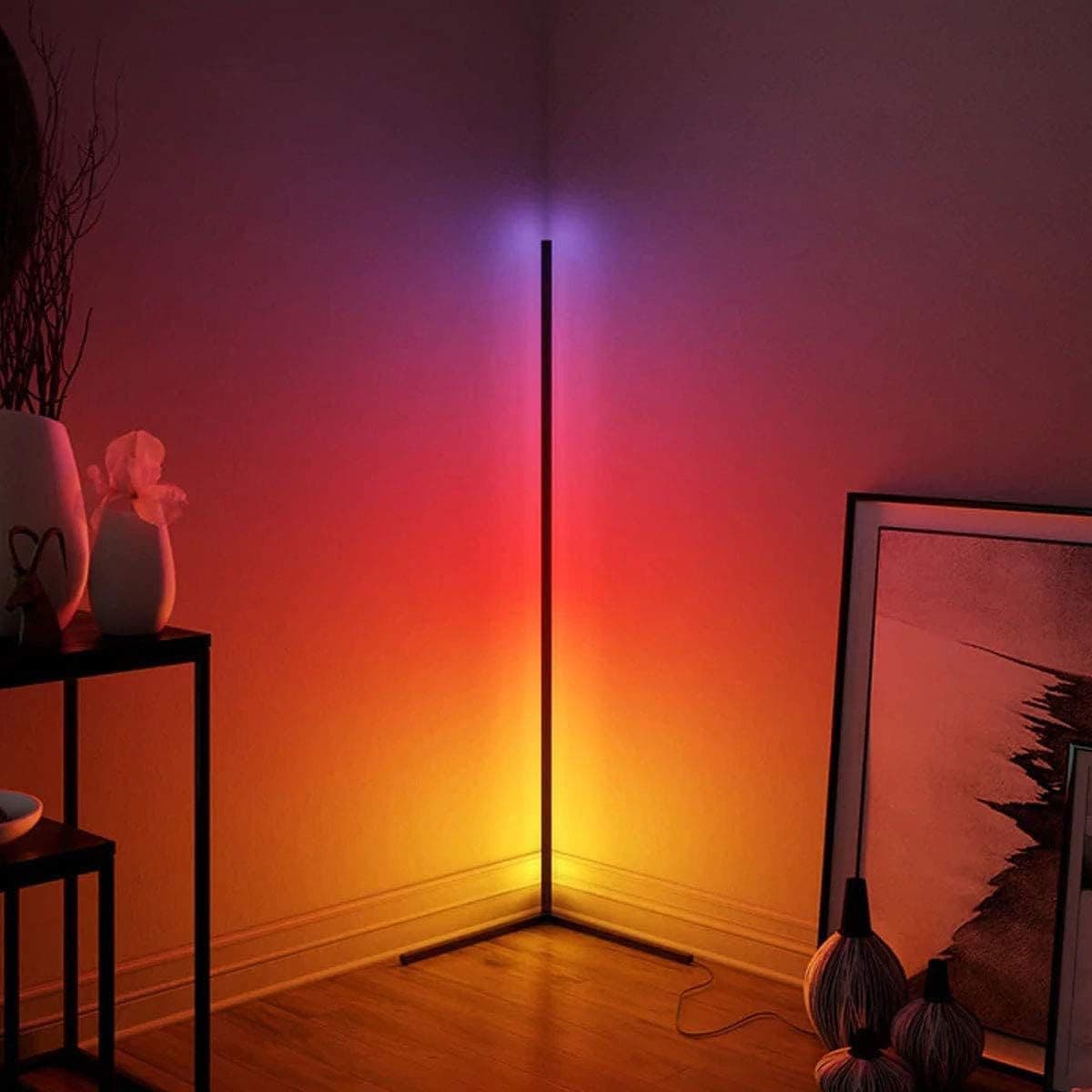 RGB corner floor lamp lit warm orange in a living room corner beside framed art