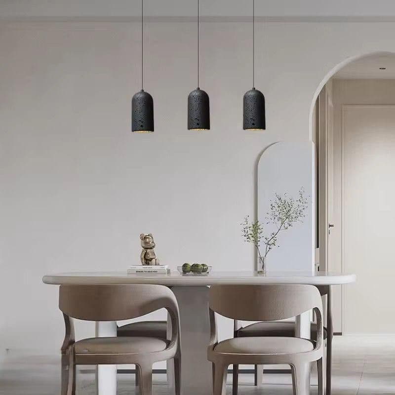Three black lava stone pendants hanging above a dining table in a modern room