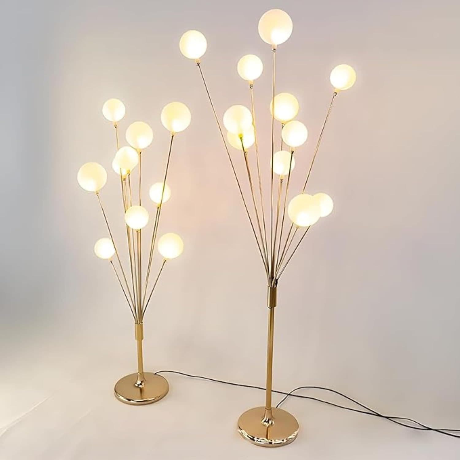 Two LED tree floor lamps lit warm white, gold branches with frosted globes