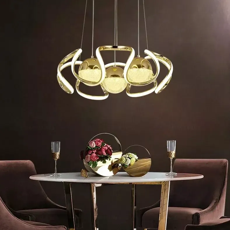 Gold ring chandelier lit above a dining table set with fruit bowl