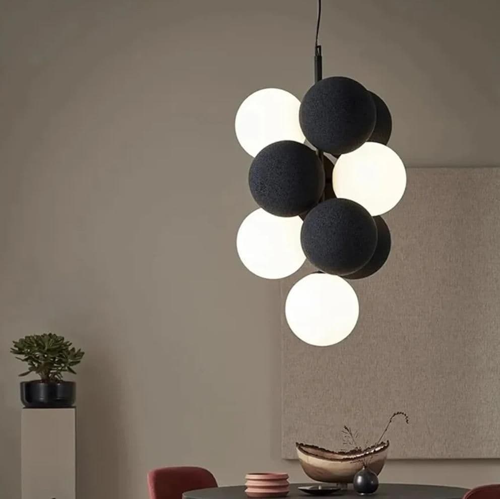 Close view of the velvet chandelier's black and white spherical shades, lit