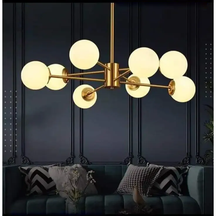 Two-tier gold globe chandelier lit warm against a dark wall