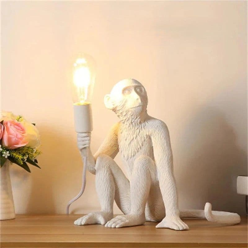 White resin monkey table lamp lit, styled with flowers