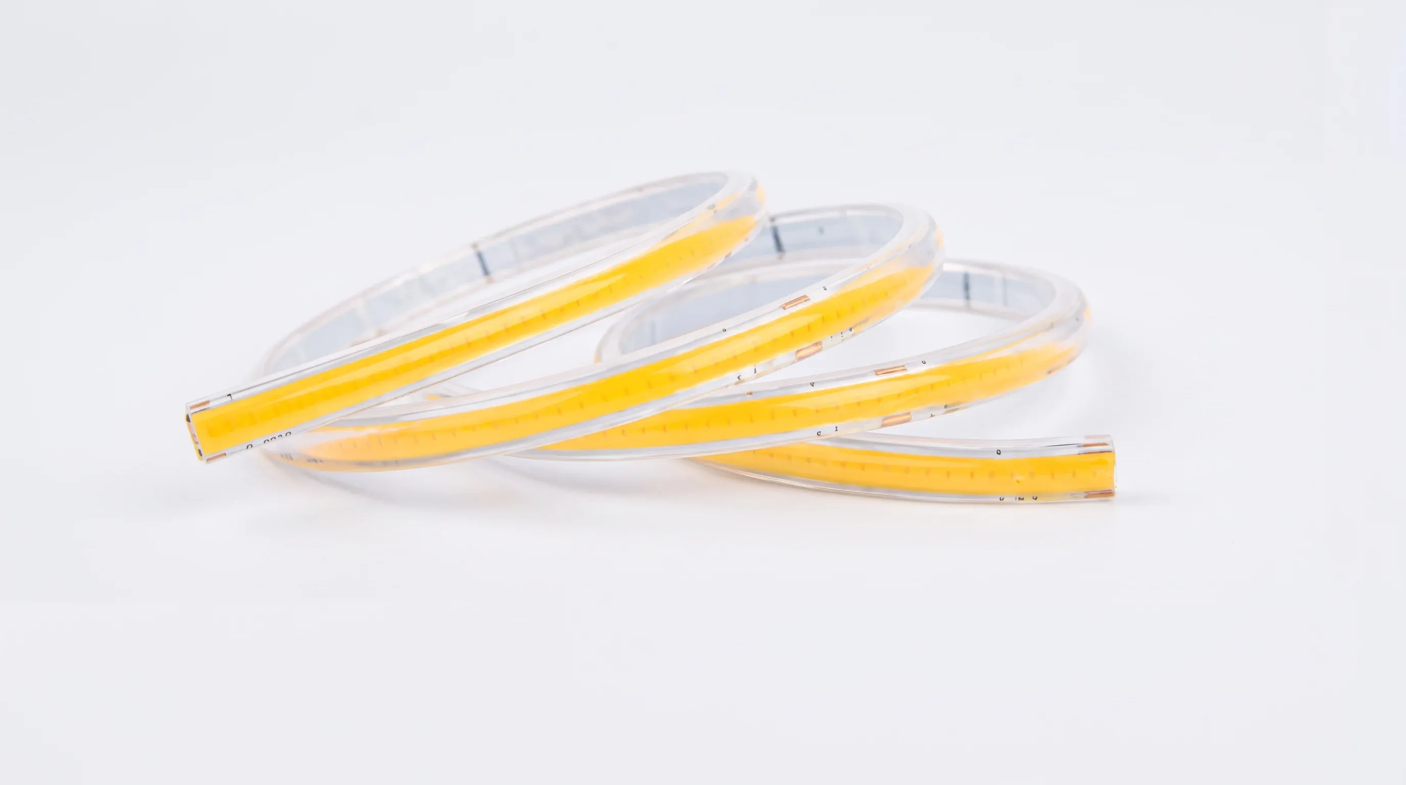 Yellow and white COB LED strip light coiled on plain background