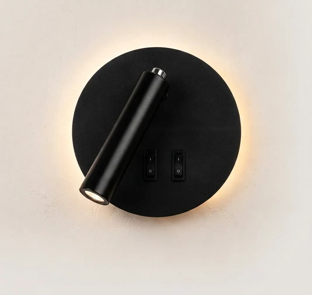 Round black LED wall light lit with warm glow.