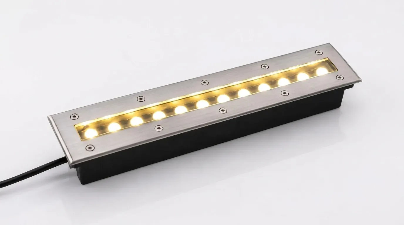 Recessed in ground linear LED light with stainless steel face and cable on plain background